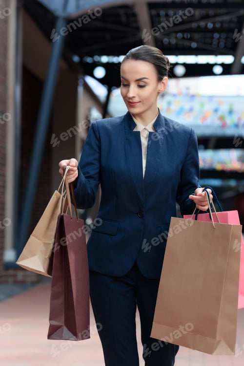 Preview: attractive businesswoman looking at shopping bags in hands