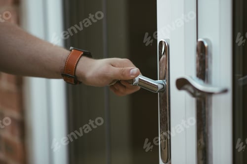 Preview: Closeup shot of a person holding a door knob and opening the door