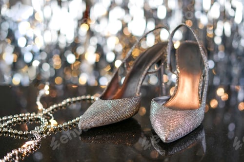 Preview: Formal evening wear, silver high heels against grey glittery background.