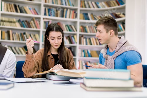 Preview: Two attractive smiling confident students, Caucasian girl and boy, sitting at the table while