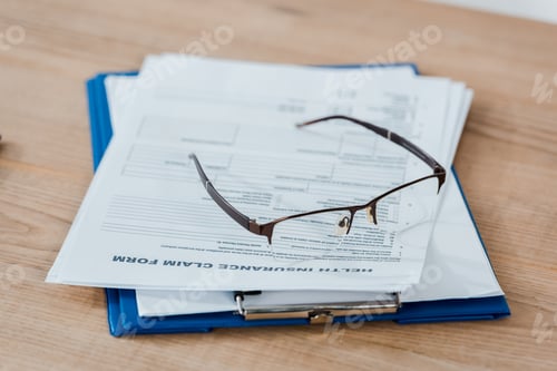 Preview: selective focus of glasses on clipboard with documents