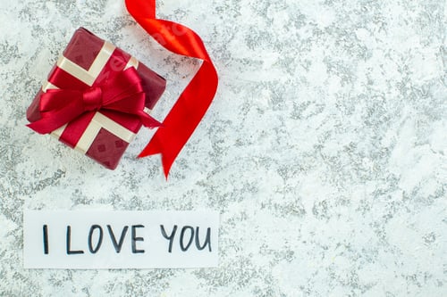 Preview: top view holiday gift box red ribbon i love you written on paper on grey table free space