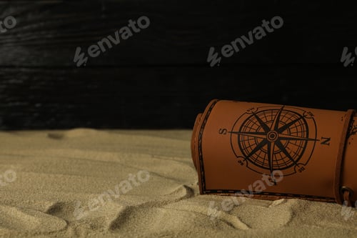 Preview: Columbus Day. A leather map lies on the sand