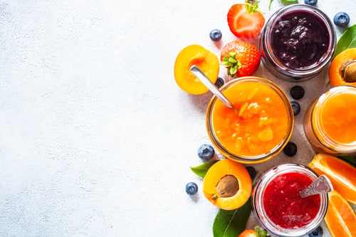 Preview: Homemade jam in glass jars at white table.