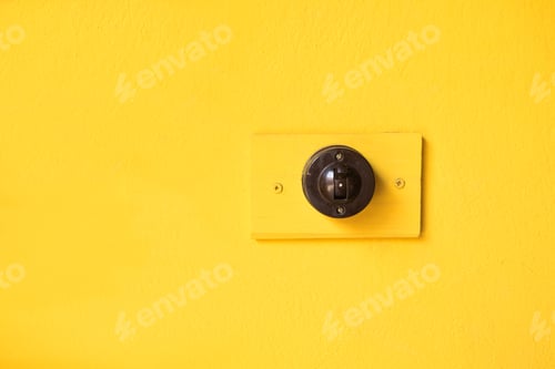 Preview: A black light switch in vintage style on a bright yellow wall