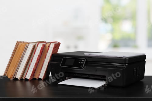 Preview: Stack of books and home printer against blurred background