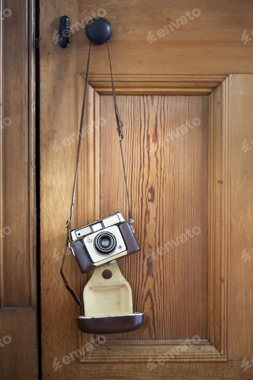 Preview: Vintage camera hanging against a wooden door
