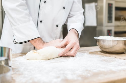 Preview: close up of baker hands with uncooked dough on cutting board