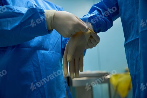 Preview: Doctor wearing medical protective gloves in operation theater at hospital