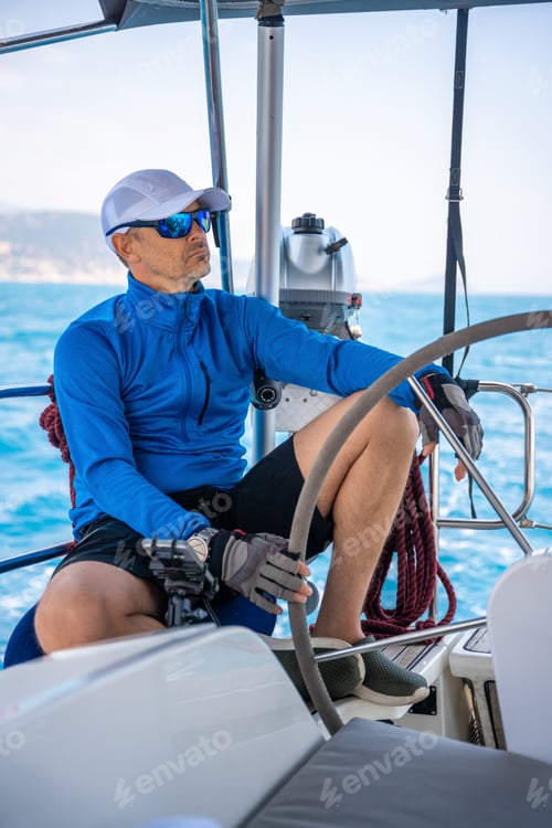 Preview: Young man captain stands at the helm and controls a sailboat during a journey by sea
