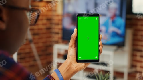 Preview: Female employee vertically holding greenscreen on smartphone