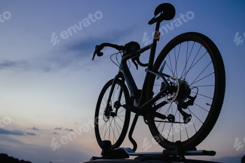Preview: A sports bike is fixed on the roof of a car. Background of the evening sky.