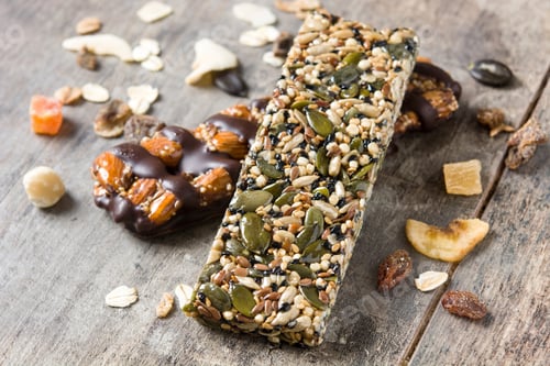 Preview: Protein bars with nuts, seeds, chocolate and dried fruits lying on wooden table
