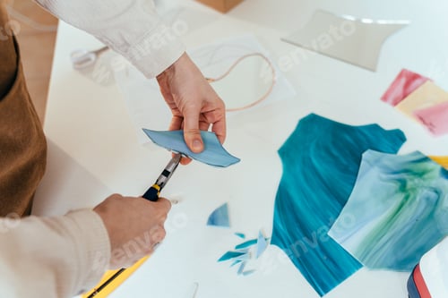 Preview: Concentrated woman taking piece of glasses for creating in art studio with stained glass windows.