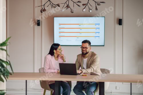 Preview: Business colleagues discussing strategy with laptop and charts on screen