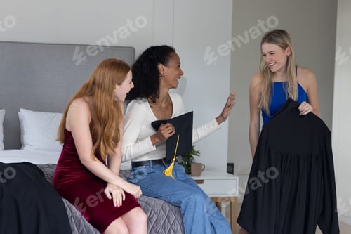 Vista previa: Chicas adolescentes preparan con entusiasmo los vestidos de graduación en el dormitorio, compartiendo risas alegres