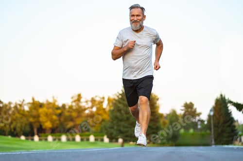 Preview: The smiling happy elderly man running on the road.