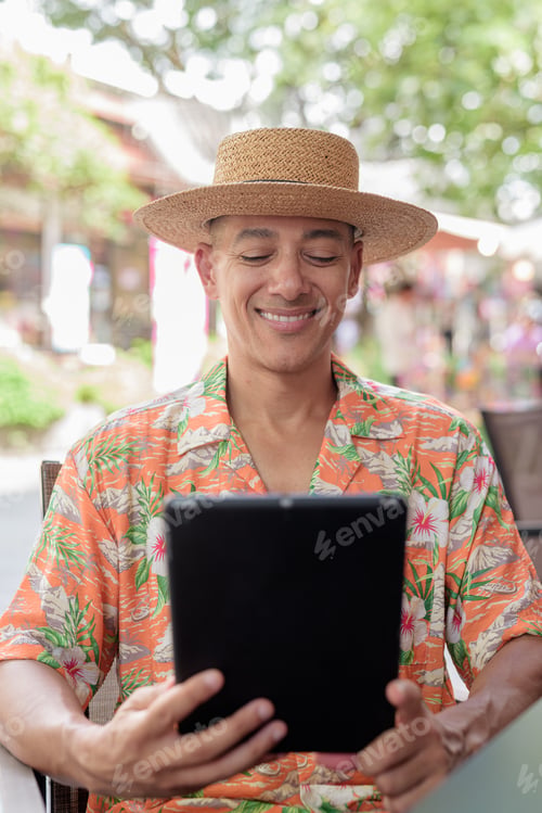 Preview: Hispanic Male Tourist Using Tablet Computer at Outdoor Cafe