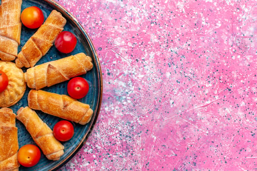 Preview: top close view sweet delicious bagels baked pastries inside tray with plums on pink desk bake pastry