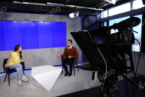 Preview: Presenters working in studio, focus on video camera