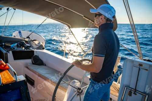 Preview: Young man captain stands at the helm and controls a sailboat during a journey by sea