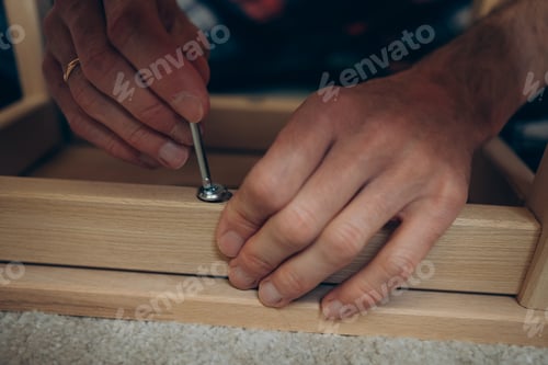 Preview: male hands assembling wooden furniture with self-tapping screws