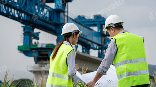 Preview: Two construction workers wearing safety gear standing in front of a large blue crane.
