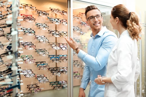 Preview: Female ophthalmologist helping man to choose glasses in optical store