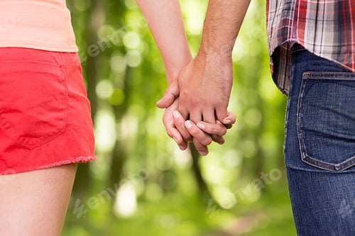 Preview: Couple holding hands. Close-up of man and woman holding hands while walking in the park