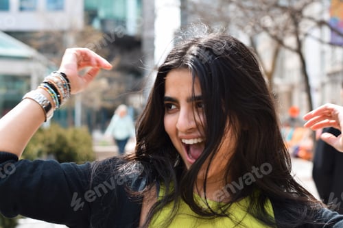 Preview: Candid portrait of happy young girl smiling laughing on city street