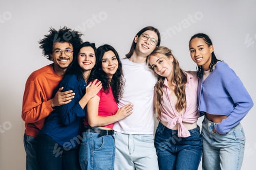 Preview: Diverse group of happy young friends embracing togetherness looking at camera