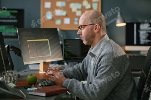 Preview: Middle Aged Caucasian Man Concentrating While Writing Code on Desktop Computer
