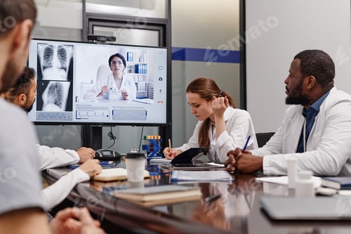 Preview: Young female medical officer making notes during digital meeting