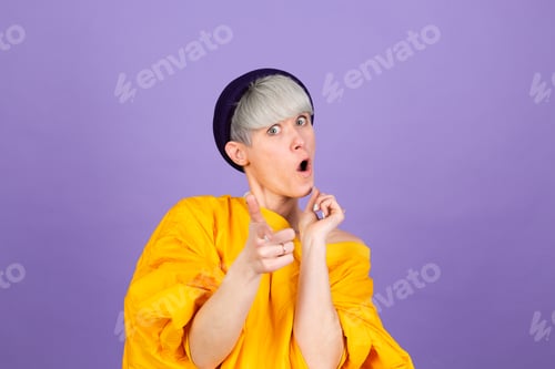 Preview: Stylish european woman on purple background point to you to camera with happy face
