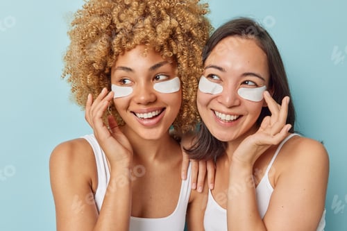 Preview: Positive mixed race women use collagen undereye patches smile gladfully put on mask from puffiness t