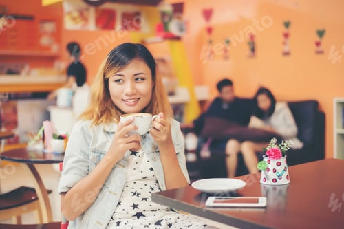 Preview: Portrait of young beautiful woman sitting in a cafe holding hot coffee.