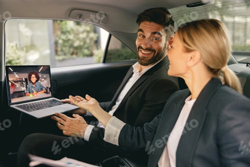 Preview: Smiling business colleagues have online meeting using laptop while sitting in car back seats