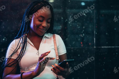 Preview: Cheerful african american woman using smartphone while in a subway