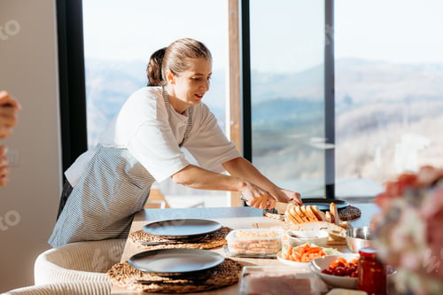Preview: Woman preparing a meal in a modern kitchen with mountain view.