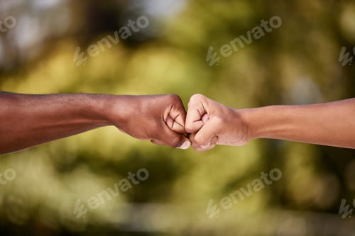 Preview: Closeup of men doing a fist bump against a blur background. Two male hands and arms punch together