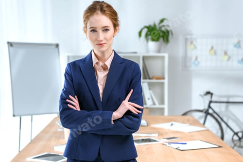 Preview: businesswoman with arms crossed looking at camera at office space