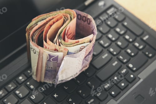 Preview: Money on a laptop keyboard. Foreign exchange rates and trading concept image.