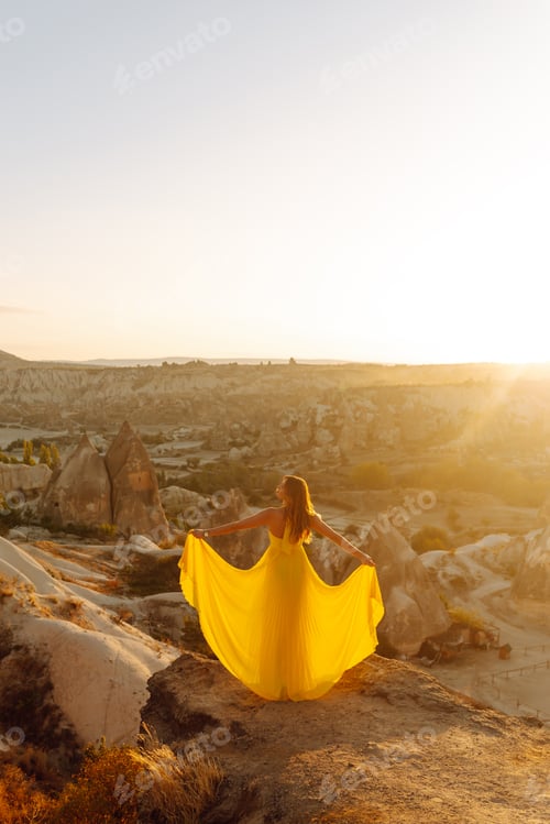 Preview: Woman stands on mountain with flying air balloons on background. Tourist Turkish region Cappadocia.