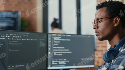 Preview: Portrait of focused software developer writing code arranging glasses sitting at desk