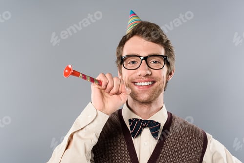 Preview: happy man in glasses and party cap holding party horn isolated on grey