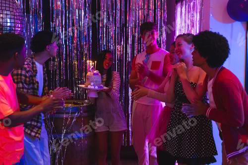 Visualização: Adolescentes comemorando aniversário com bolo e velas em uma festa vibrante