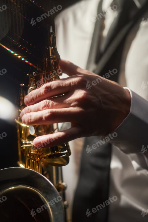 Preview: Male Musician Pushing Keys Of Saxophone Playing Music in Contrast Light on Stage