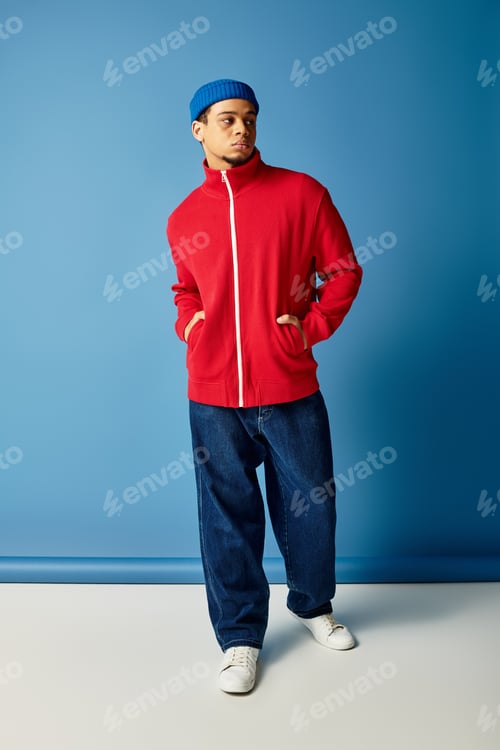 Preview: Stylish young man in a beanie poses confidently against a vibrant blue backdrop