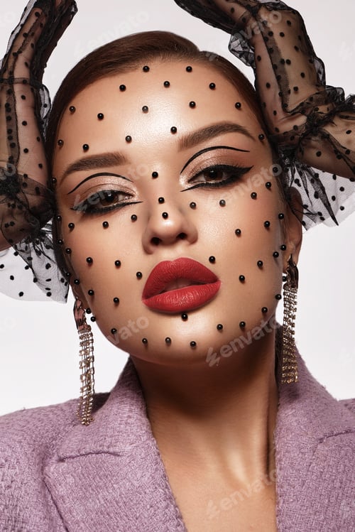 Preview: Portrait of a beautiful woman with creative makeup, black beads on her face in a fashion style