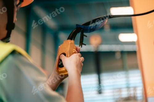 Preview: Asian woman engineer uses remote control panel to lift up or down of power trolley crane